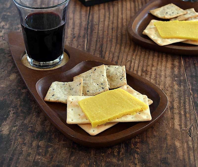 Vegan sliceable cheese with crackers, wine, on a party tray.