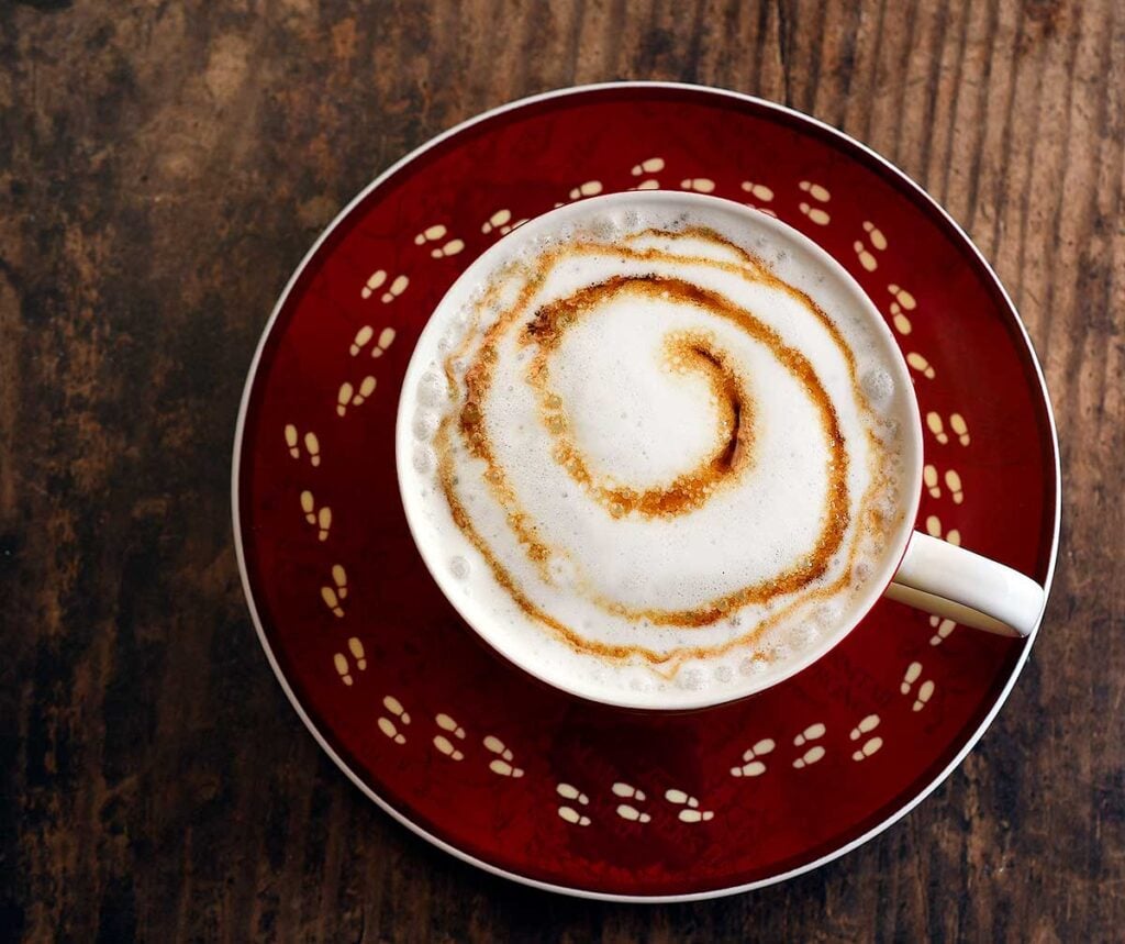Hot butterbeer made with vegan homemade syrup topped with foamed milk and a butterbeer syrup swirl.