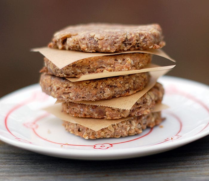 Make Your Own Banana Flax Vegan Dog Biscuits Round banana dog biscuits piled on top of each other with parchment in between served on plate
