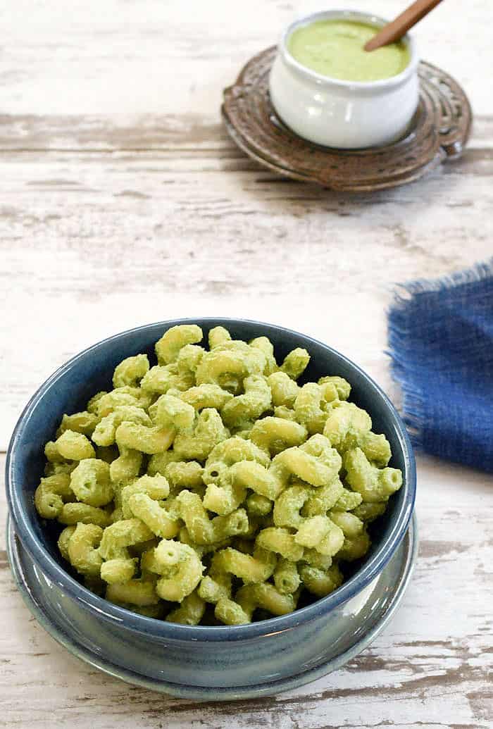 macaroni with Kale Stem Pasta Sauce in a blue bowl with sauce beside it.