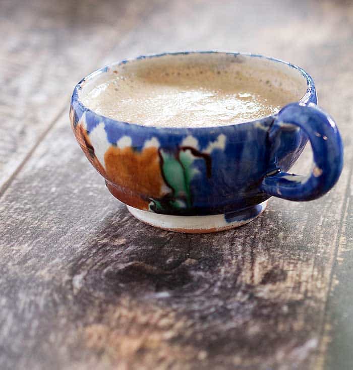 Slow Cooker vegan maple pumpkin latte in a rustic blue and orange painted pottery cup