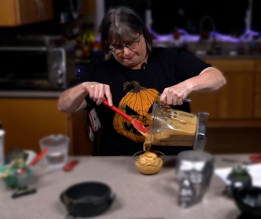 Kathy pouring the blended pub cheese from the Vitamix to a bowl.