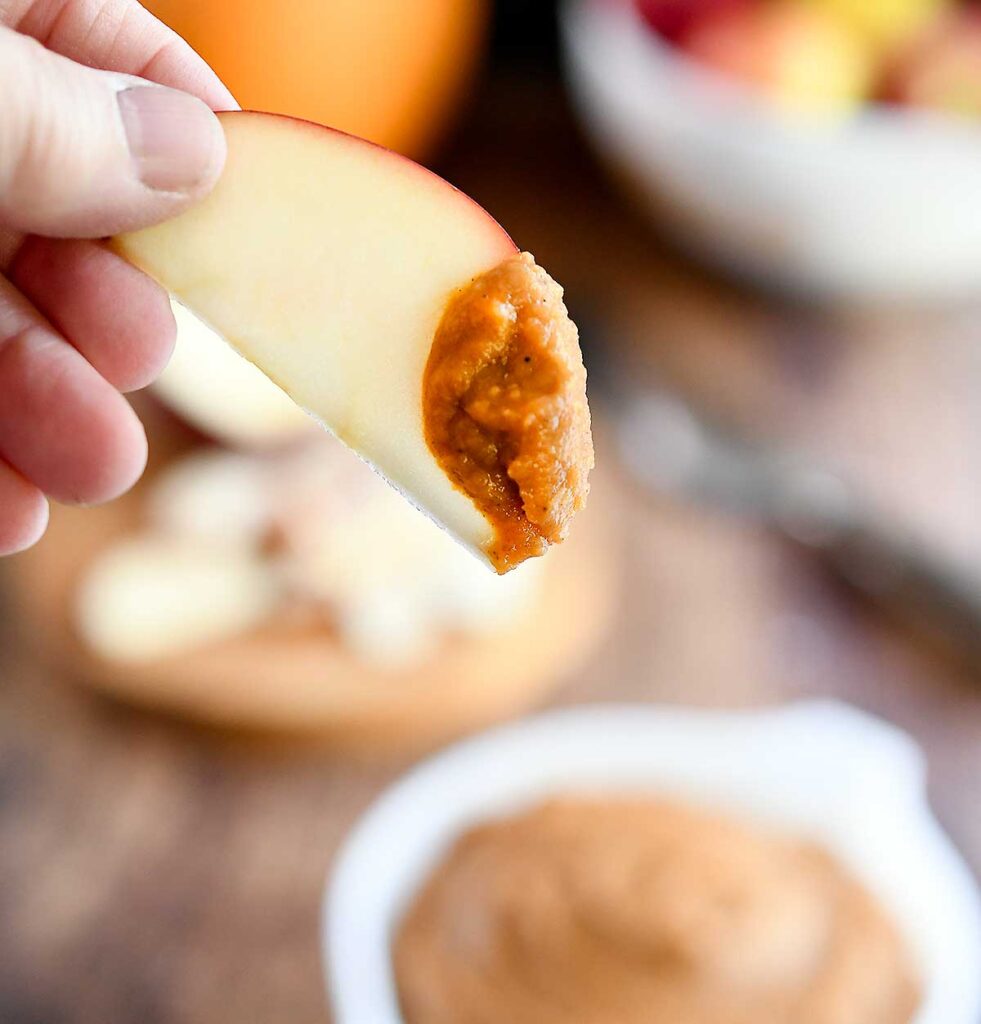 An apple slice dipped into the pumpkin dessert hummus